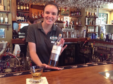 Bartender Monika Faber holding a bottle of Macallan 10 year old with fellow bartender Robbie Seyler in the background at MacAllisters Grill & Tavern.