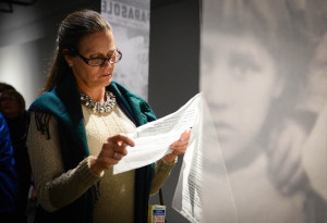 Mary Jo Baras reads the story of one of the survivors featured in Wojtek Sawa's exhibit, "The Wall Speaks," which opened to the public in January at the Florida Holocaust Museum in St. Petersburg. (Staff photo / Rachel S. O'Hara)