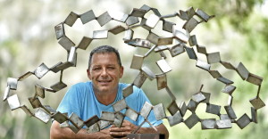 Duncan Chamberlain with an early, untitled work made from scavenged metal pieces called coupons. / HERALD-TRIBUNE PHOTO BY THOMAS A. BENDER