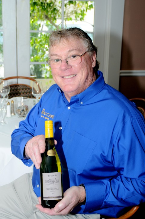 J.P. Knaggs, owner of The Bijou Café in downtown Sarasota, poses with a bottle of Le Jardin Cuvée Prestige, a Loire Chardonnay produced exclusively for The Bijou Café in collaboration with Les Frères Couillaud winery in France. COURTESY PHOTO / EVELYN ENGLAND 