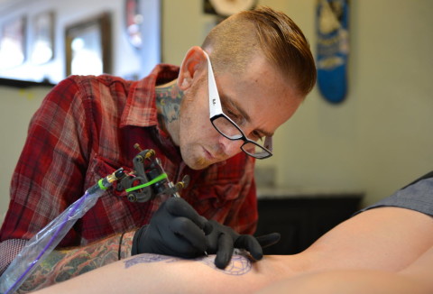 Matt Norris of Webber Tattoo Company works on a tattoo of an owl for Felicia Mitchell.