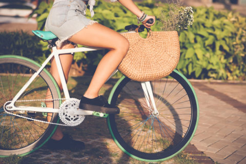 Cropped image of girl in denim shorts riding bicycle
